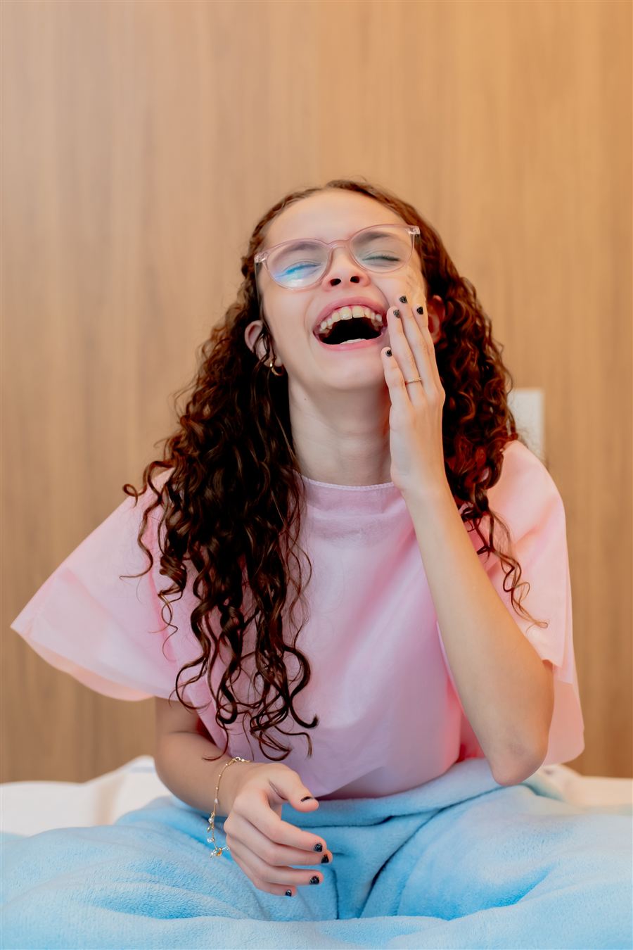 Paciente rindo, sentada na cama de uma suíte do Saine
