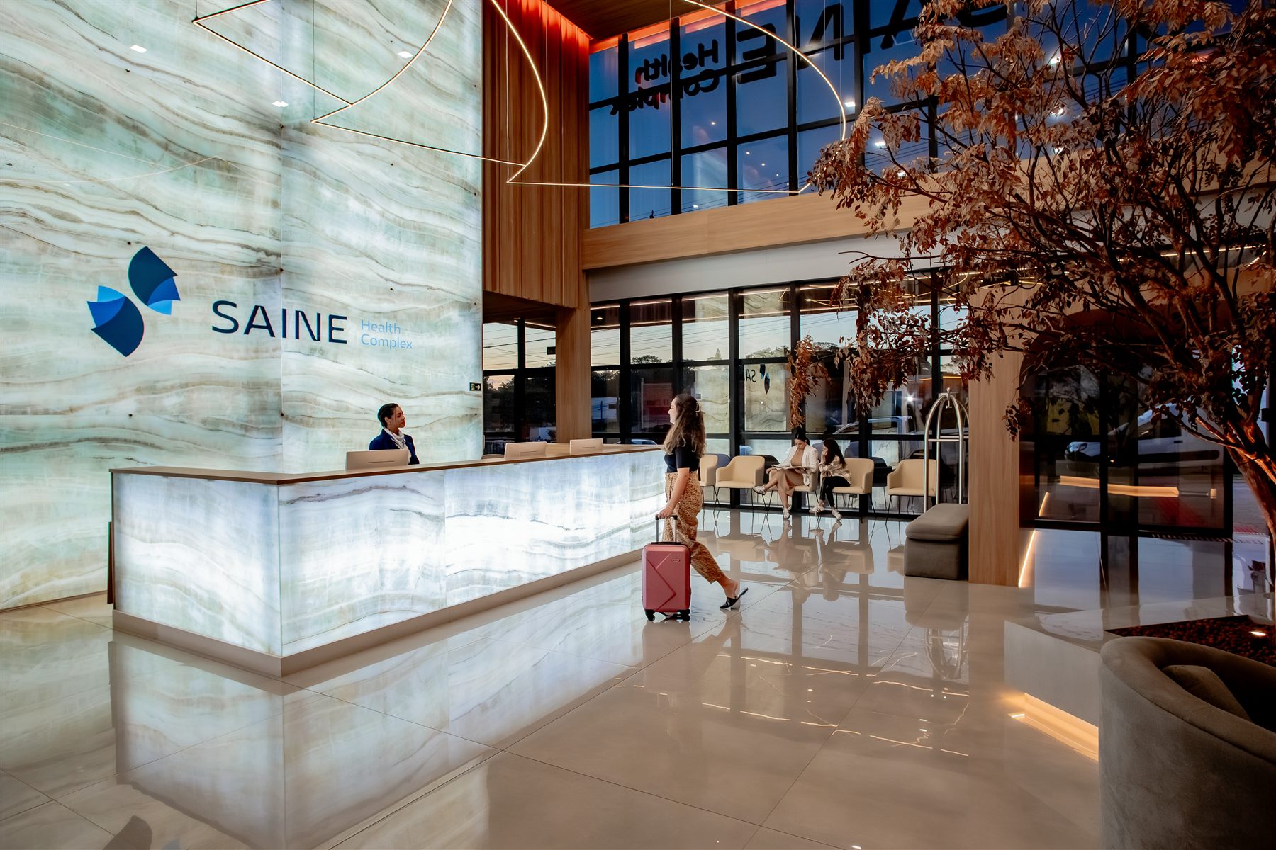 Saguão do Saine Health Complex, com recepção revestida em ônix retroiluminado